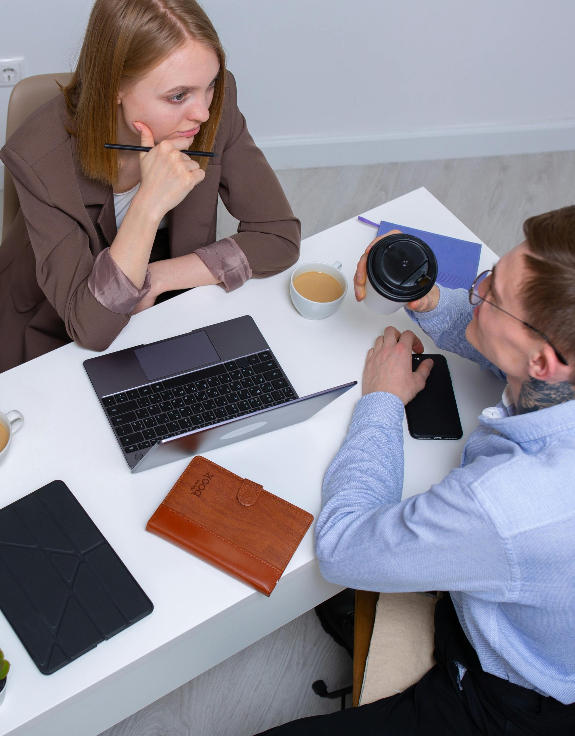 Top view of coworkers engaging in a business meeting with laptops and notebooks on the table.
